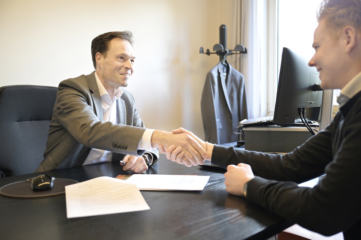 Dos personas estrechando la mano en una oficina tras firmar un acuerdo
